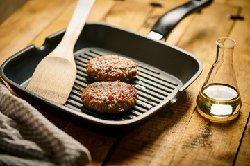 Closeup of juicy burgers fried on black grill pan