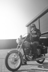 Fototapeta na wymiar Black and white. Portrait of a middle-aged man, an old biker in a leather jacket on a retro bike, vintage classic Soviet motorcycle. concept of freedom and style, a hobby for life. vertical photo