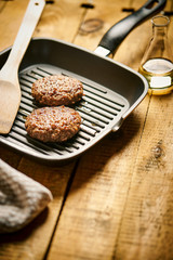 Closeup of juicy burgers fried on black grill pan