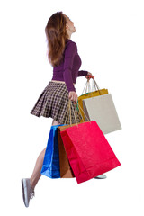 side view of a woman jumping with shopping bags.