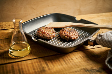 Closeup of juicy burgers fried on black grill pan