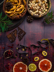 Food background with christmas spices, dried apples, nuts, citrus fruits, cydonia, cranberries, raisin, and baking dish on wooden background.Top view with copy space