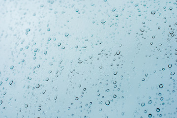 Window splashed with raindrops. Blue glass with drops of water. Misted glass.