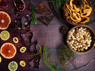Food background with christmas spices, dried apples, nuts, citrus fruits, cydonia, cranberries, raisin, and baking dish on wooden background.Top view with copy space