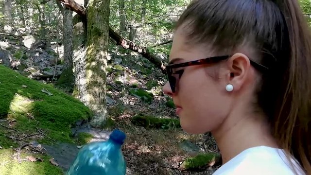 Forest flies and insects bothering young girl trying to drink water from blue bottle in deep forest, SLOMO, STILL