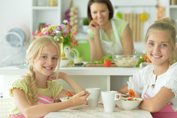 Portrait of girls eating delicious fresh salad in kitchen