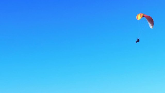 Nice drone view of paramotor flying untroubled and having fun under the blue sky