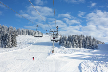 Fototapeta na wymiar Wintersports fans riding the ski lift to empty pistes.