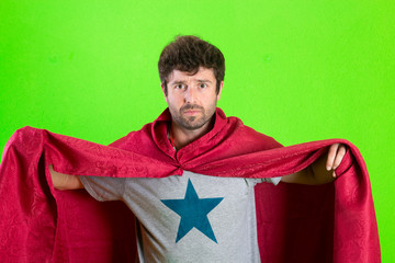 Young crazy super hero serious expression, confused and doubtful on green background