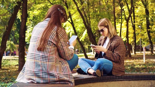 Hipster girls surfing social media on smartphones outdoors