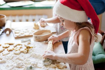 Kids cooking Christmas cookies in cozy kitchen. Child prepares holiday food for family. Cute little...