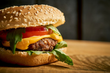 Close up of tasty hamburger on wooden table and black background