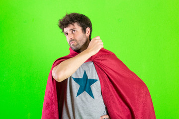 Young crazy super hero serious expression, confused and doubtful on green background