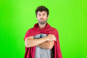 Young crazy super hero serious expression, confused and doubtful on green background