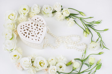 white flowers lined with a frame and a jewelry box in the shape of a heart, pearl beads