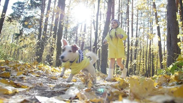 Concept of pets, family and friendship. little cute girl runs through the autumn forest with a dog