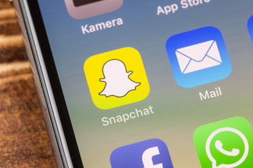 METTINGEN, GERMANY - NOVEMBER 9, 2018: Close up to snapchat app on the screen of an iPhone X with personalized background