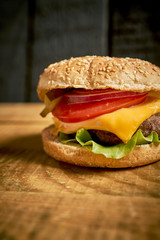 Close up of tasty hamburger on wooden table and black background