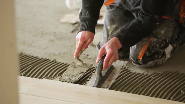Construction Worker Putting On New Wood Flooring Using Adhesive