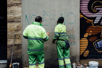 employés municipaux nettoient un mur tagué  en espagne 