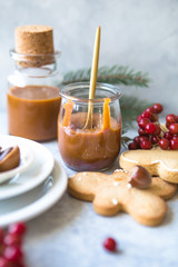 Homemade salted caramel sauce with cookies in jar on concrete background.