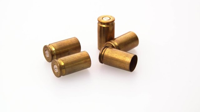 Used rustic 9mm pistol bullet shell casing rounds on a white background, rotating shot