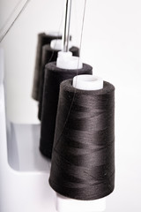 Black thread bobbins on overlock. Sewing machine.