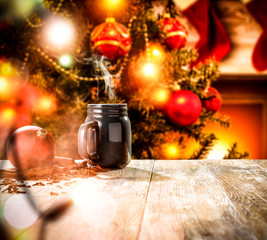 A wooden table with space for your advertising products. Blurred great green Christmas tree and Fireplace with flames and red socks of Santa Claus background.
