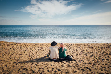Fototapeta premium un couple assis sur la plage regarde la mer, les vagues et l'horizon pendant les vacances