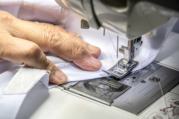 The seamstress is using the sewing machine.