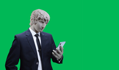 Modern art collage. Concept portrait of a  businessman  holding mobile smartphone using app texting sms message. Gypsum head of of Antinous. Man in suit. On a orange background.