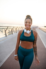 Fototapeta premium Dark-skinned young woman smiling after morning run