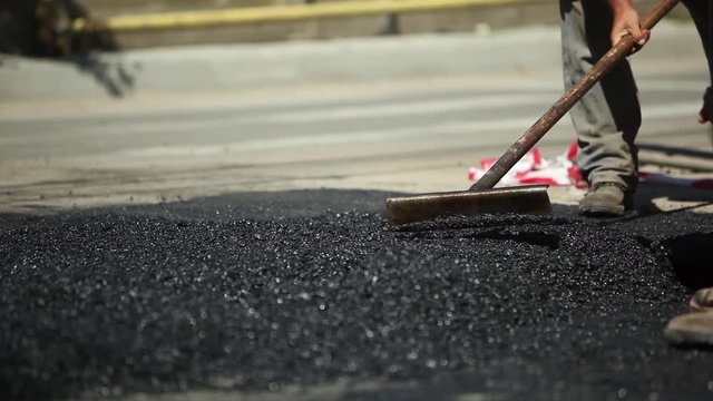 Hot Asphalt Paving Machinery. Steamroller And Workers Shoveling Asphalt
