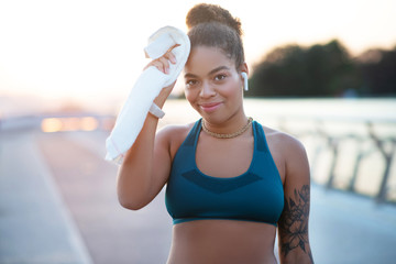 Woman wearing earphones drying sweat after workout