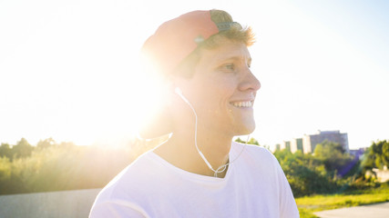 CLOSE UP Young Caucasian male with cap listening the music and sitting on bmx bicycle in park on...