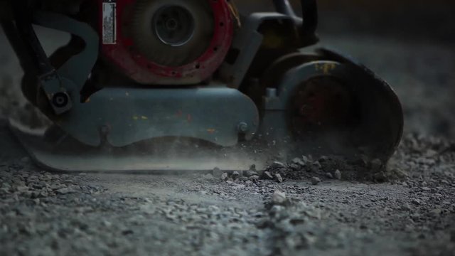 Stone Pavement Road Construction Workers. Leveling The Sand Layer with a finishing plate compactor
