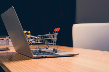 Shopping cart on a laptop keyboard at home.Shopping is quick and convenient with your fingertips, anytime, anywhere.Online shopping and commerce concept.