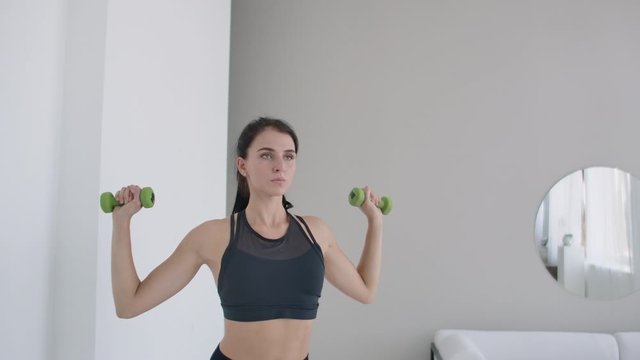 Raise the dumbbells over your head performing exercises for the shoulders. Training at home in the apartment