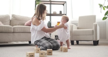 Mother holding hands and dancing with her baby daughter at home