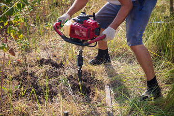 Worker drills the ground for the fence