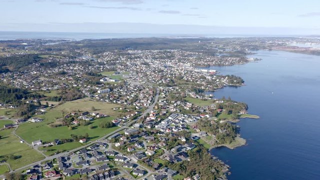 Aerial view above suburban waterfront ocean residential homes rooftops estate. Aerial wide left orbit across neighbourhood.