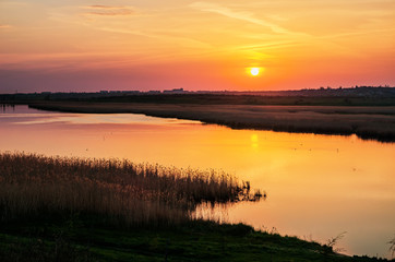 Fototapeta na wymiar orange sunset over water in river