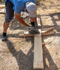 A worker cuts a wooden board at a construction site