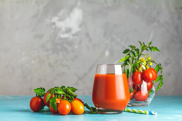 Glass of fresh delicious jummy red tomato juice and fresh tomatoes on light concrete surface. Close up. Gmo free. Natural good food