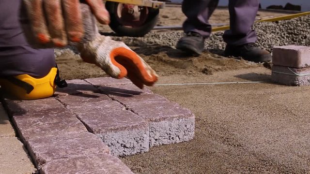 Stone Pavement Road Construction Workers Wearing Knee Protection. Using hammer to fit stone tiles