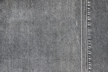 Texture of a gray denim fabric. Two pieces of fabric stitched together