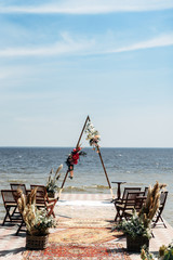 Wedding ceremony on the riverside. Festive triangular wedding arch decorated with flowers