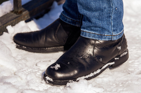 Legs of a man in shoes and jeans on the snow in winter