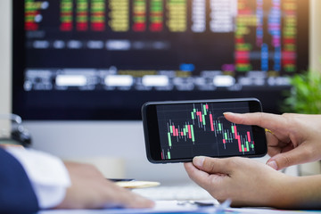 Businessman checking stock market data. He using a mobile phone. Analysis economy data on forex earn graph.