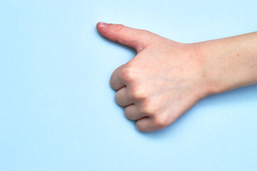 symbol thumb shown by a child's hand on blue paper background